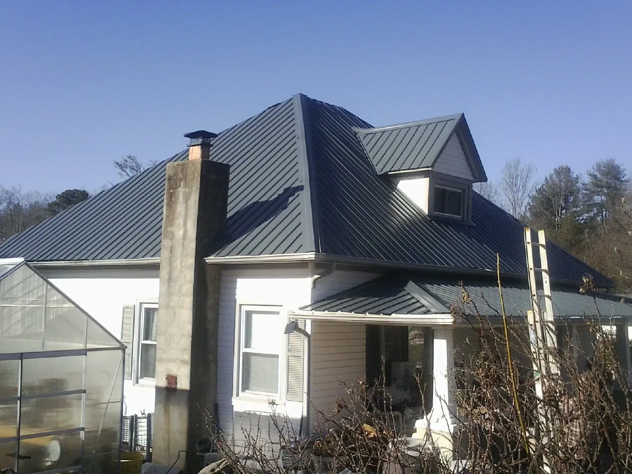 Dark blue standing seam metal roof on a white farmhouse with dormer — Slate & Tile Roof Repair by Roofing Brothers in Twin Lakes