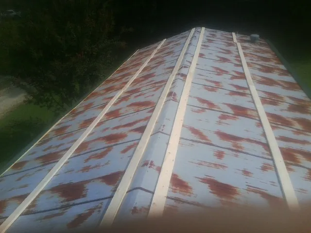 Rusted metal roof panels with new wood purlins before replacement — Storm Damage Roof Repair in Twin Lakes by Roofing Brothers