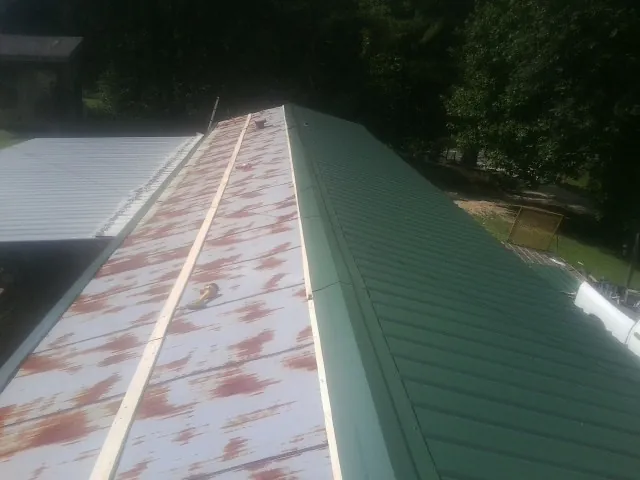 Old rusted panels beside newly installed green metal roofing — Wind Damage Roof Repair by Roofing Brothers in Twin Lakes