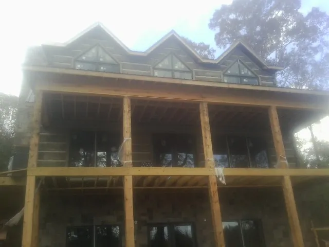Dormers and porch framing on a large log home under construction — Roof Coating work by our crew in Twin Lakes