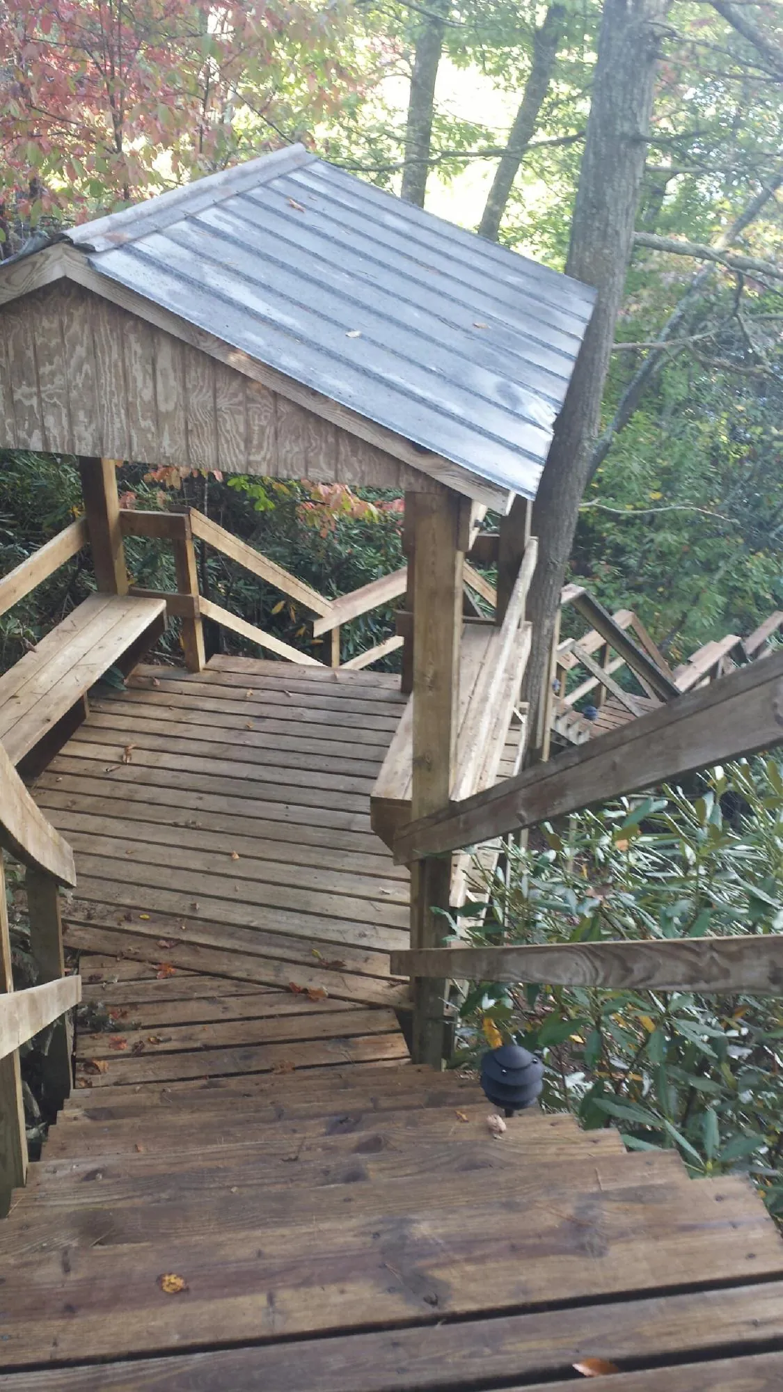 Metal roofed shelter over wooden steps on a wooded walkway — Skylight Repair & Installation work by our crew in Twin Lakes