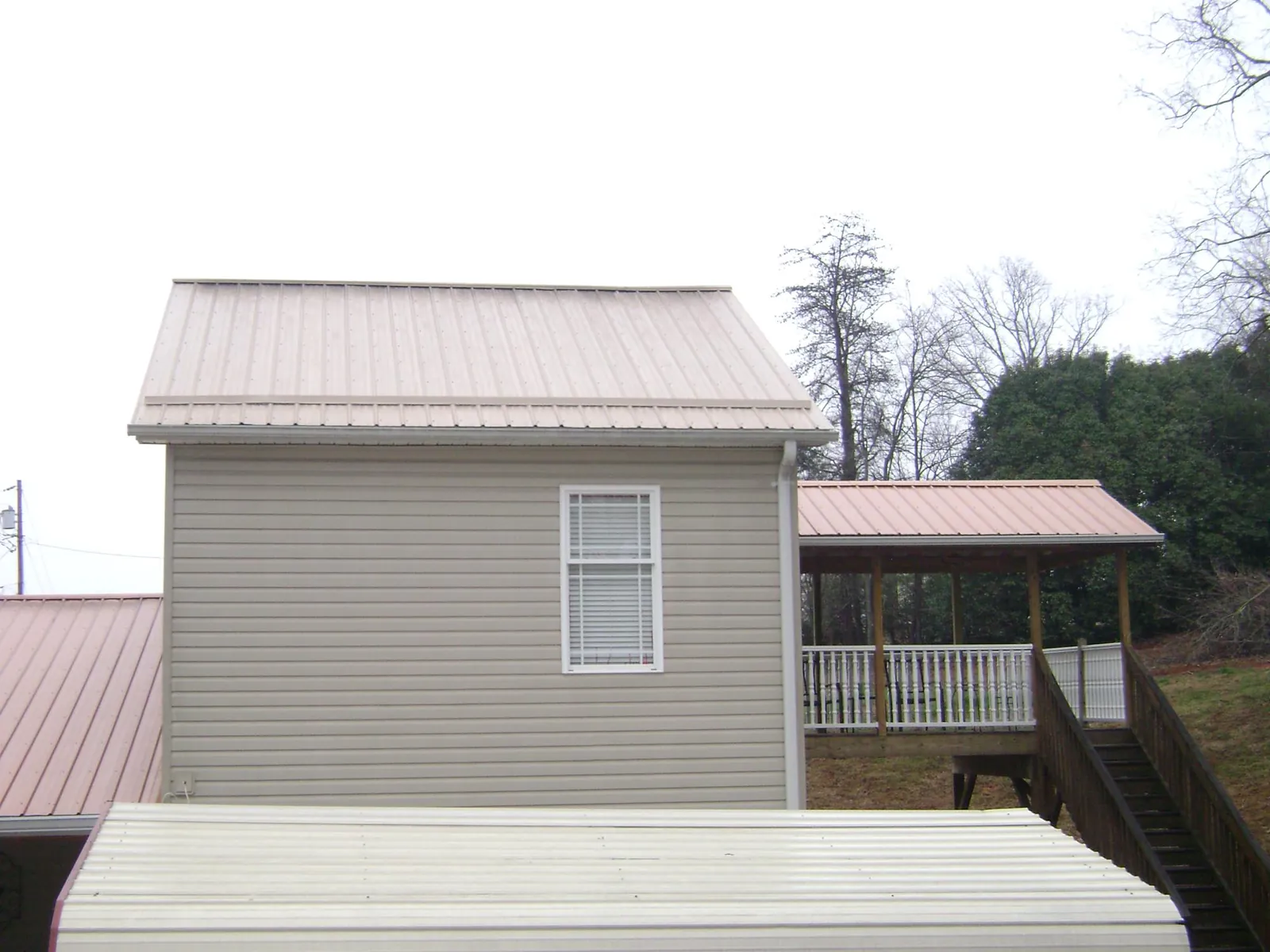 Tan metal roofs on a two story addition and attached porch, from a Roof Replacement job in Twin Lakes