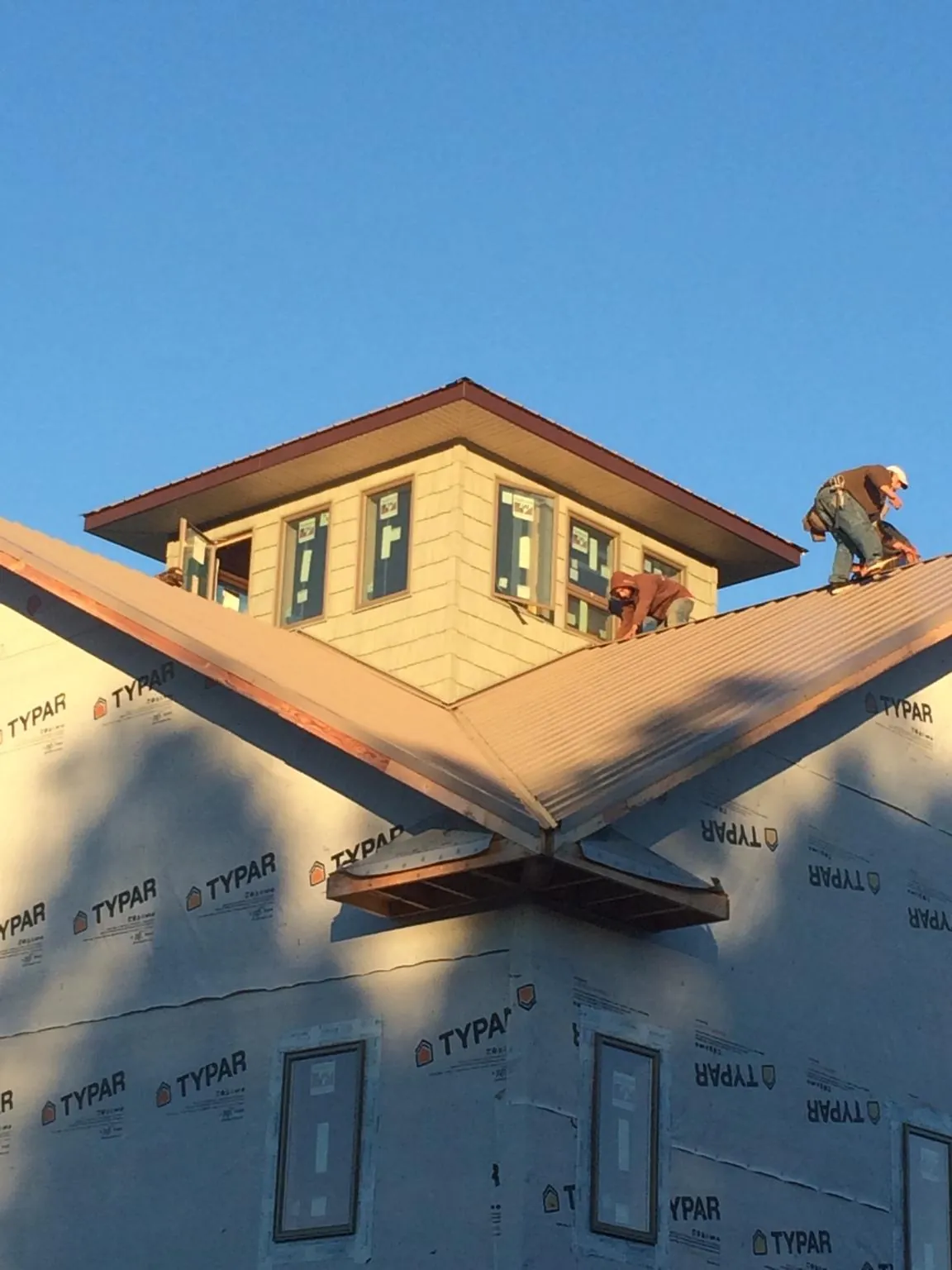 Roofers working around a rooftop cupola on a new metal roof at sunset — Roof Waterproofing in Twin Lakes by Roofing Brothers